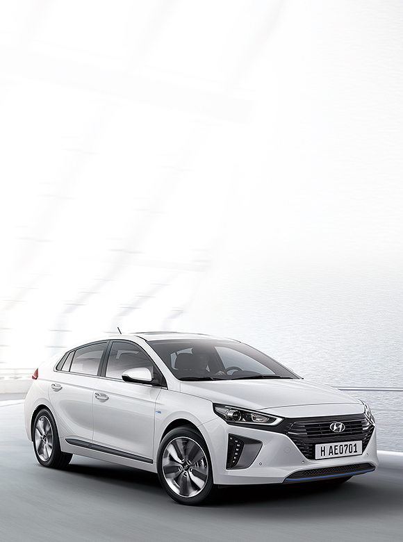 White Ioniq Hybrid is driving on the road next to an ocean