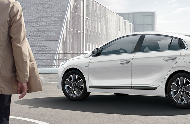 A man approaching to white Ioniq Hybrid parked outdoor