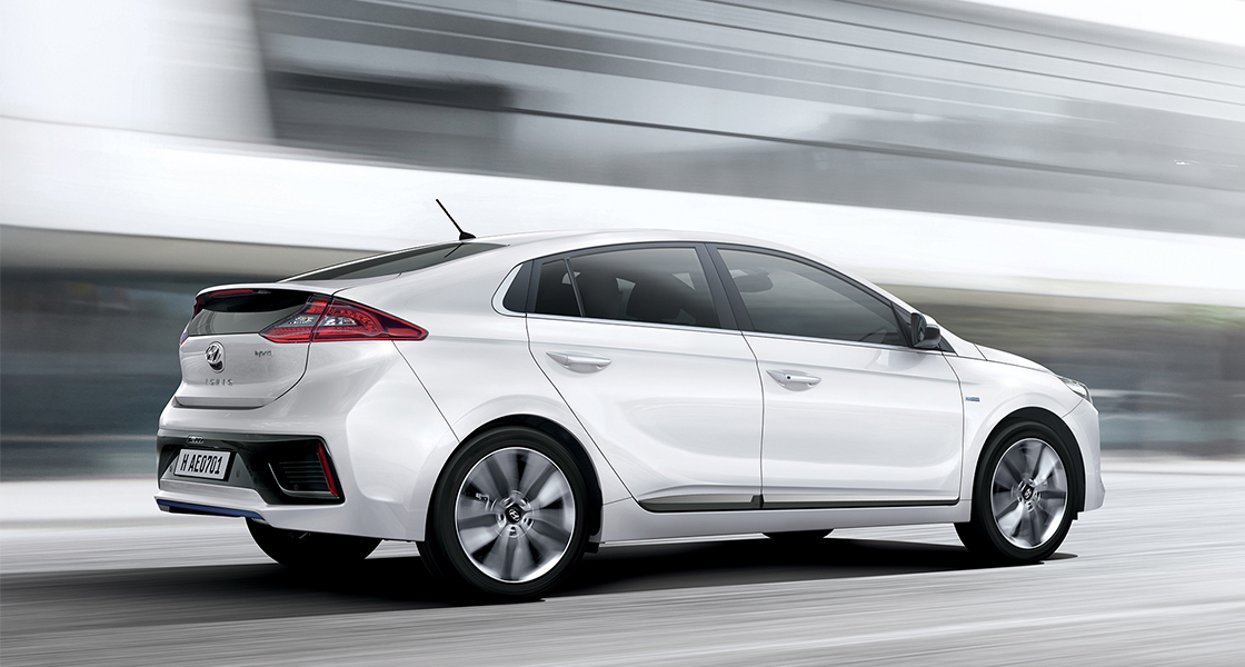 Side view of white Ioniq hybrid driving fast on the road