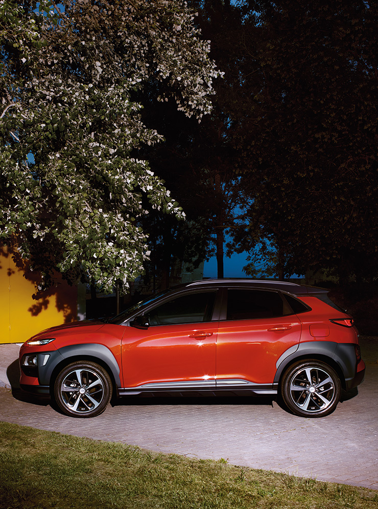 Left side view of red kona parked on the road