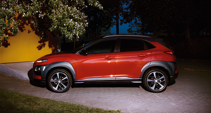 left side view of red kona parked on the road